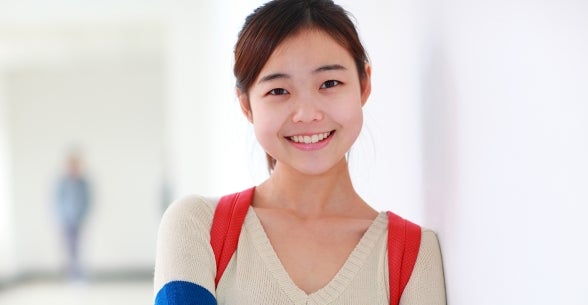 Image of a young woman smiling in a hallway.