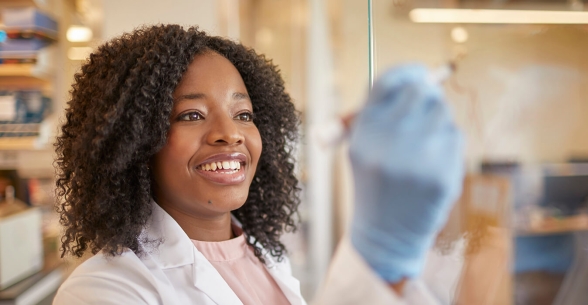 Woman in blue gloves and a lab coat writing on a glass board.