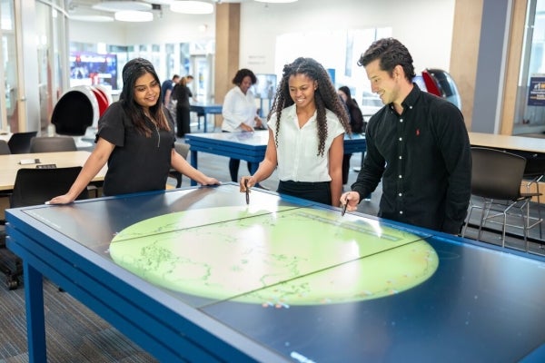 Image of Thunderbird students using a collaborative touch screen table.