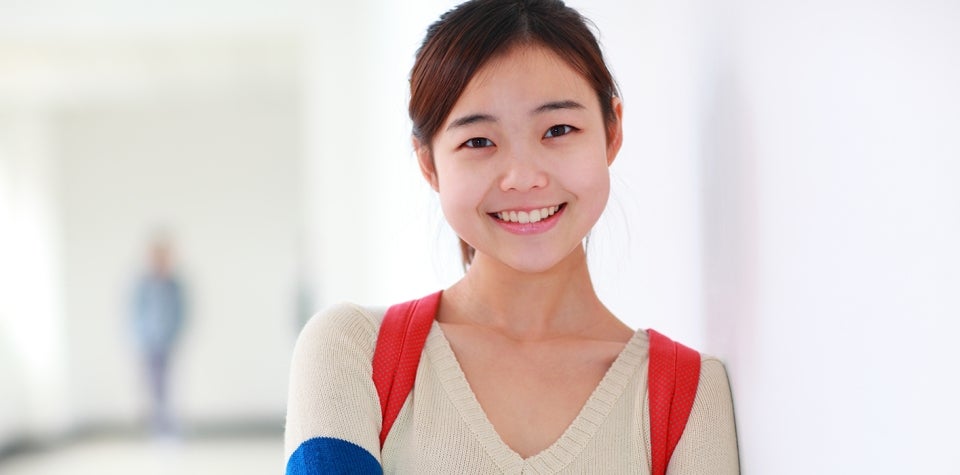 Imagem de uma jovem mulher sorrindo em um corredor.