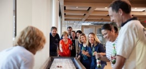 Image of staff and alumni playing a game of shuffleboard in the Thunderbird Pub