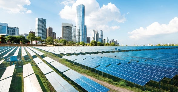 Image of a solar panel field in front of a modern city.
