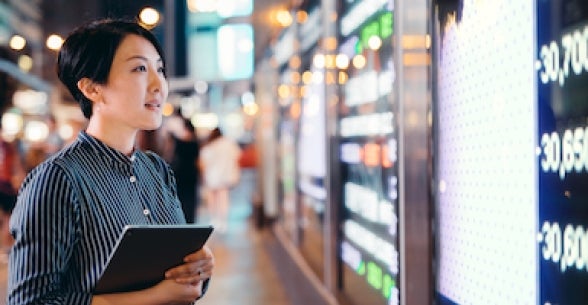 Woman holding iPad stares at display with financial information