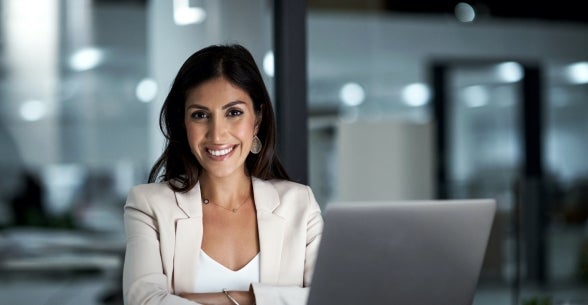 Businesswoman smile while sitting in her office near her laptop.
