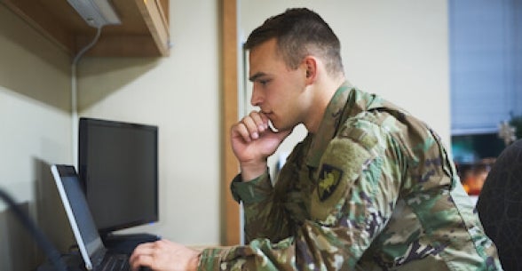 Soldier sitting at a desk looking at a laptop