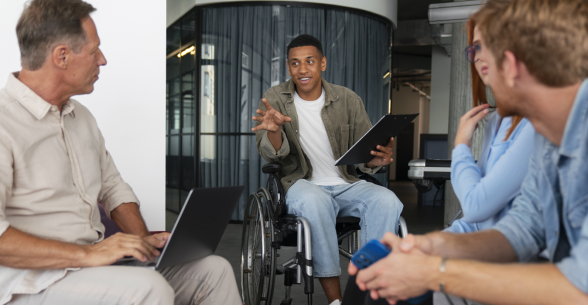 Colleagues, one in a wheelchair, meet and discuss in an office setting