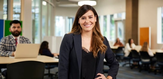 Image of a Thunderbird graduate student in a blazer smiling with her hand on her hip in a classroom in Thunderbird School of Global Management's new Global Headquarters.