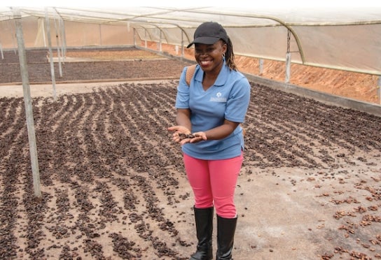 A thunderbird student stands in a cocoa drying center while on a Global Challenge Lab consulting trip overseas