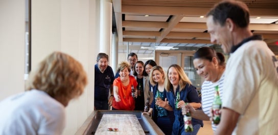 Image of staff and alumni playing a game of shuffleboard in the Thunderbird Pub