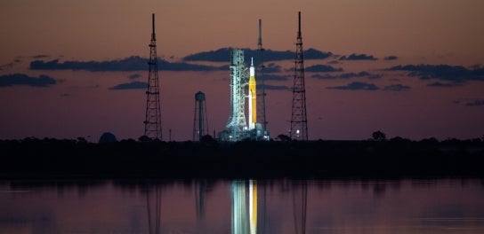 Image of space rocket at night reflected in water