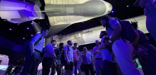 Image of students in the Space Leadership program underneath a rocket during a site visit.